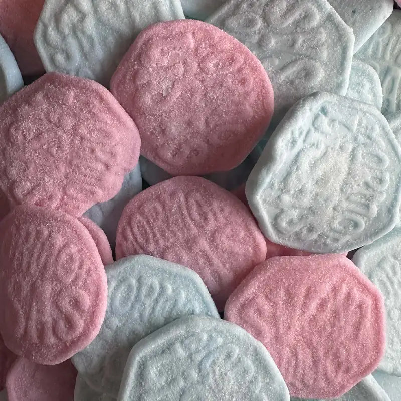 Close-up of pink and light blue hexagonal candy with embossed designs.